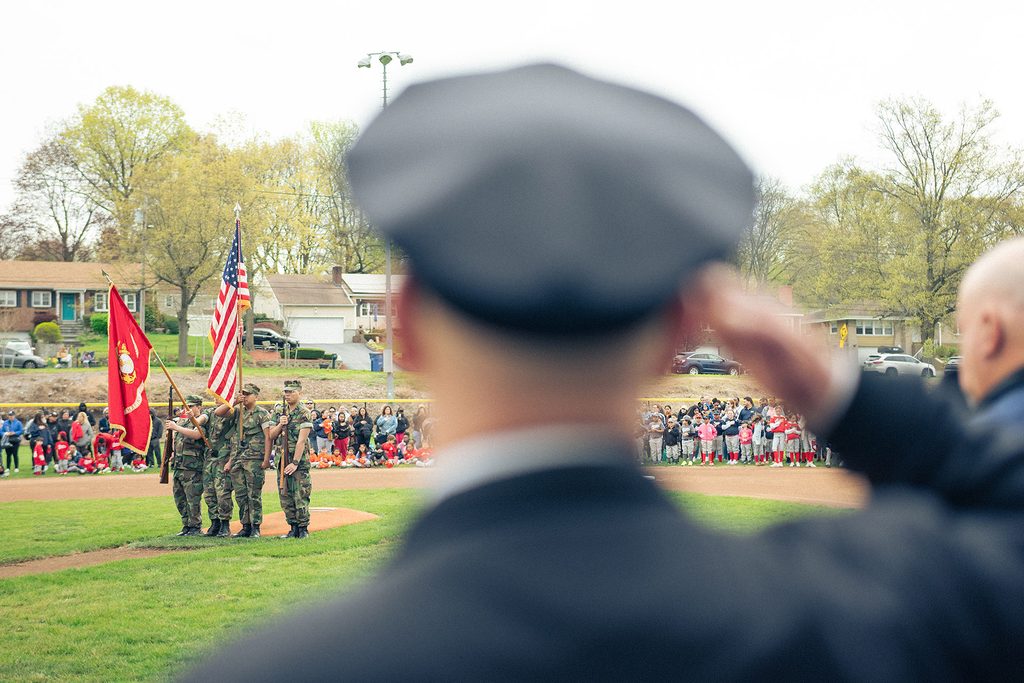 New Haven Police chief David Zannelli stands at attention to salute the flag at the Annex Little League Opening Day celebration.